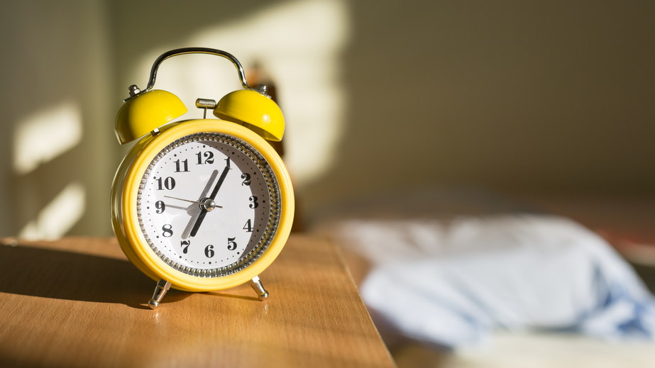 Yellow alarm clock on a night table, close up.